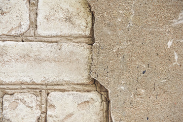 The old wall of white brick with a broken, cracked plaster. Abstract background.