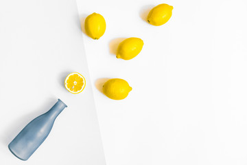 Water bottle and a few lemons on pastel grey and white background. Flat lay, top view
