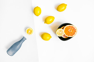Water bottle and a few lemons on pastel grey and white background. Flat lay, top view