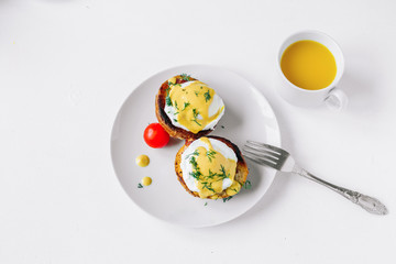 Traditional breakfast. Eggs benedict  on a plate with orange juice and tomatoes top view