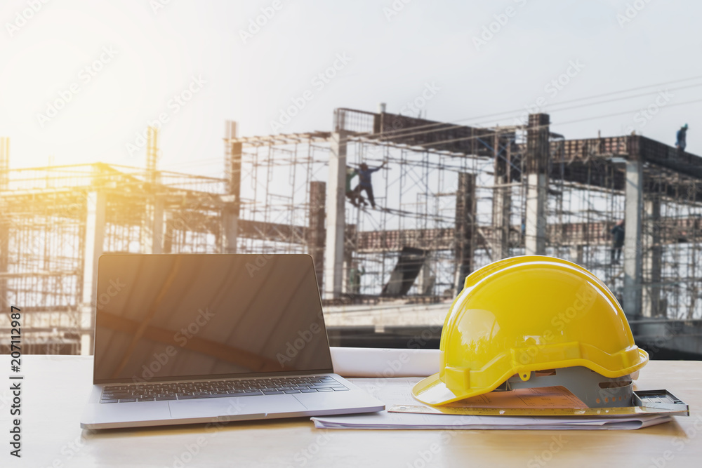 Wall mural safety helmet and computer laptop on table in concstruction site