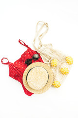 Summer female fashion stylish composition. Red dress, straw, string bag, sunglasses and lemons on white background. Flat lay, top view.