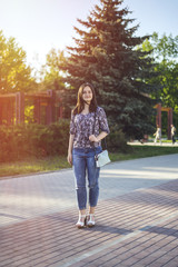 Fototapeta premium Girl with handbag walks in park.