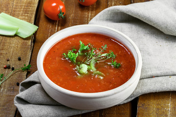 Bowl of gazpacho, bread and vegetables on a table. Tasty Spanish vegan soup.