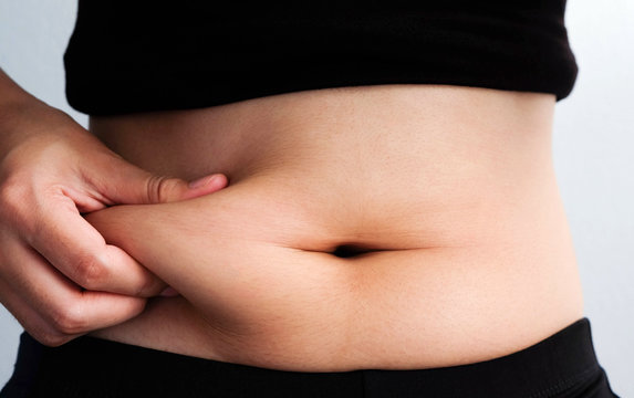 woman hand catching fat body belly paunch , diabetic risk factor .