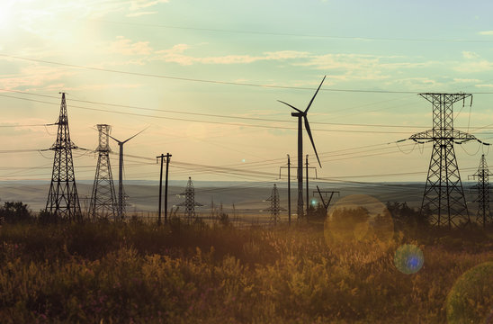 Wind-driven generators (wind generators), support of high-voltage power lines, wires, against the background of the sunshine sky