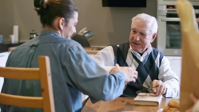 Slowmo of young male social worker shaking hand of elderly man with grey hair, then giving him household bills