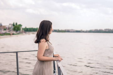 Fototapeta na wymiar Girl is dressed at the lake. Brunette woman in gray summer dress