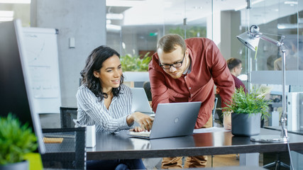 In the Busy Corporate Office Male and Female Have Work Related Discussion, Using Personal Computer....