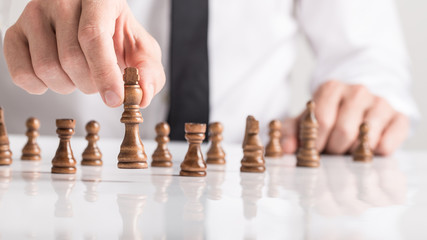 Businessman playing a game of chess on white table in a close up view of his hand