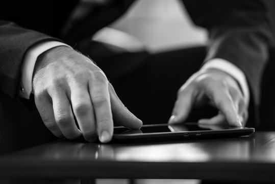 Businessman sitting at black table navigating a tablet computer