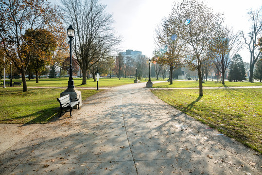 Empty Path Lined with Benches and Street Lights in a Downtown Park on a Sunny Autumn Morning