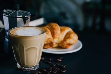 Latte art ,Croissant and moka pot with Roasted coffee on black background in the morning and instagram style filter photo vintage tone