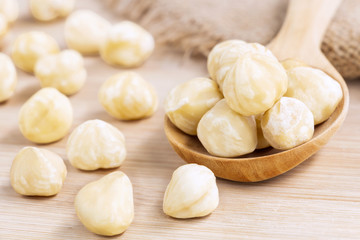 Hazelnuts nut peeled on the wooden spoon with sackcloth on wood table background with empty space for text.