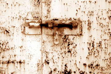 Old padlock on metal gate in orange tone.