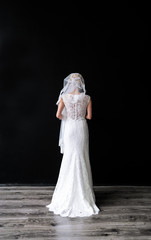 Fototapeta na wymiar Bride wearing wedding dress at black studio background