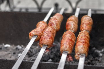 Sausages strung on a skewer are fried on coals