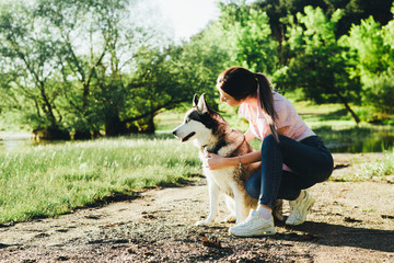 A young girl is training a dog of the Husky breed.