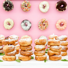Freshly baked doughnuts in composition on pink wall.