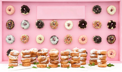 Freshly baked doughnuts in composition on pink wall.