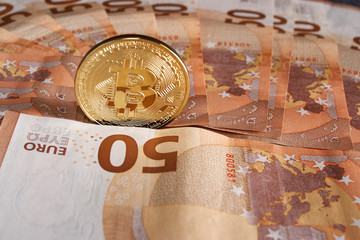 Studio shot of bitcoin physical golden coin on 50 euro bills banknotes. Bitcoin is a blockchain crypto currency
