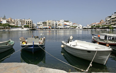 Fototapeta na wymiar The white boats on the coast of the lake and white houses and cafes in the small mediterranean town on the sunny day