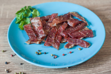 pieces of meat snacks with spices on a blue plate
