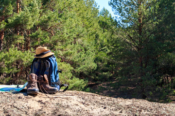 Tourist backpack with hiking boots, hat, compass and map on the glade in pine forest