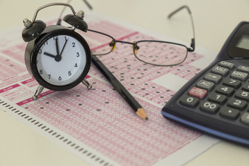 optical form and student selection and placement test,clock,glasses,pen,hand and ruler on the table.Stress of University exam.