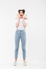 Full length photo of excited lovely woman with double buns hairstyle screaming and raising hands at face in surprise, isolated over white background