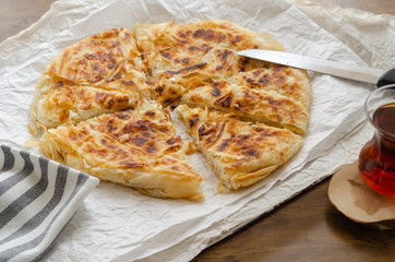 Sliced cheese pastry on the table, next to the turkish tea.