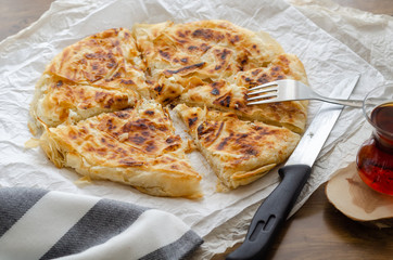 Sliced cheese pastry on the table, next to the turkish tea.