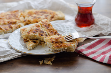Sliced cheese pastry on the table, next to the turkish tea.(shallow depth of field)