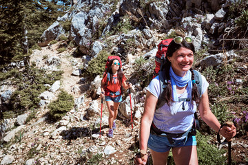 Summer hike in the mountains with a backpack and tent along the path to the top.