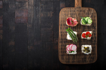 Obraz na płótnie Canvas Set of different mini sandwiches on a wooden board.