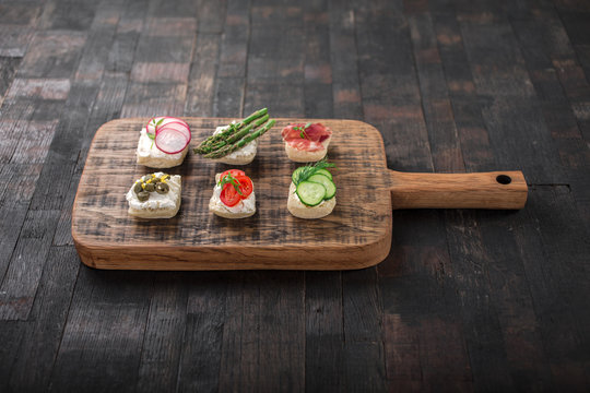 Set of different mini sandwiches on a wooden board.