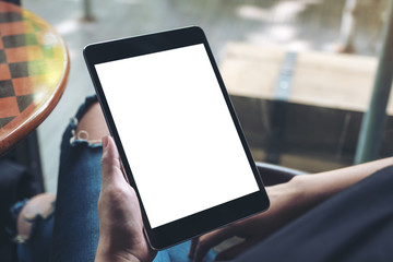 Mockup image of a woman sitting cross legged and holding black tablet pc with blank white desktop screen