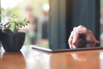 Closeup image of a woman's hands pointing , touching and using tablet pc with tree pot on table