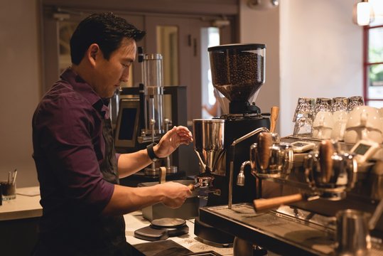 Side view of male waiter preparing coffee in cafe