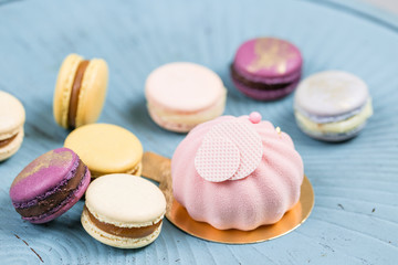 Pink mousse-cake. French macaroon dessert and flowers eucalyptus on a turquoise background. pastel colors