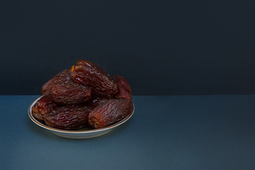 The Concept Of Ramadan. Large dates in a plate on a cold dark background with shadows.  Space for the text on the right.