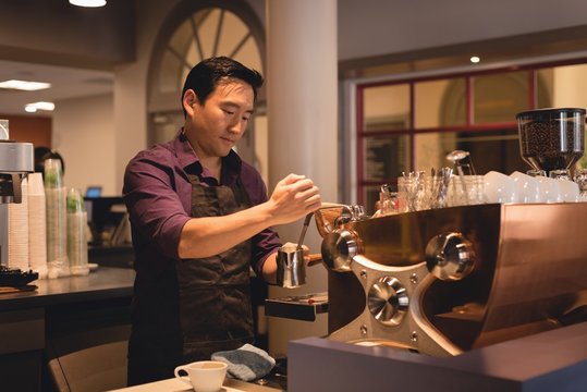 Male Waiter Preparing Coffee In Cafe