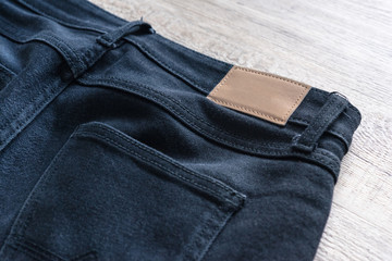 Back of jeans on wood background with leather label.