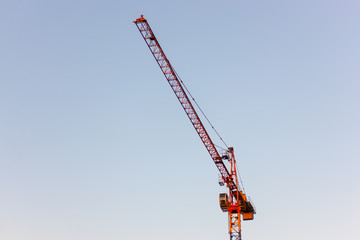 Red construction crane against clear, bright blue sky - development in the city- copy space, design element