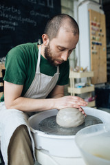 Handcrafted on a potter's wheel,Hands make clay from various items for home and sale in the store and at the exhibition, ceramic items are made in hand, stylish bearded young man makes products 