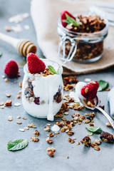 home made granola and yogurt in a glass on a neutral grey background