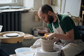 Handcrafted on a potter's wheel,Hands make clay from various items for home and sale in the store and at the exhibition, ceramic items are made in hand, stylish bearded young man makes products 