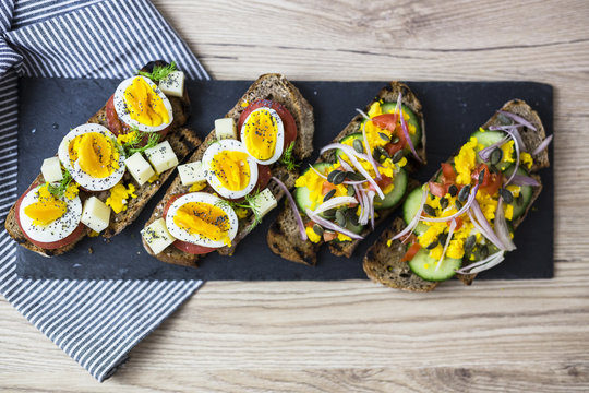 Vegetarian breakfast with bread, eggs and tomato slices and cucumber slices on slate