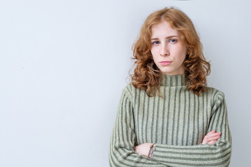 Portrait of aggravated sad woman with long red hair with crossed hands expressing her dissatisfaction and disconent. Insult teenager. People and emotions concept