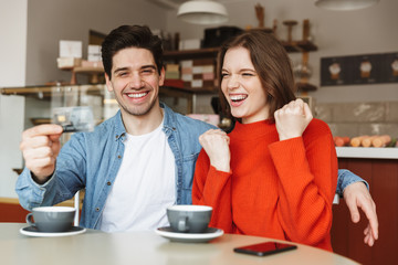 Happy young couple sitting at the cafe table
